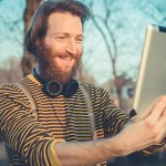 young bearded stylish handsome hipster man using tablet